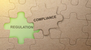 Piece of missing jigsaw puzzle with compliance text over colored background.