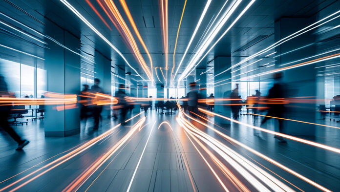 Motion blur shows silhouettes of people moving in an office