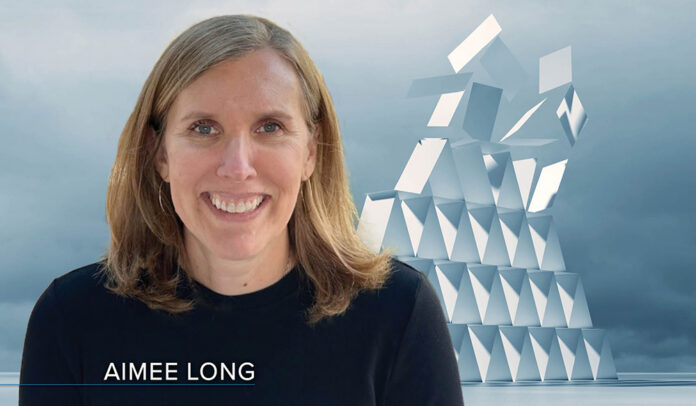 Headshot of Aimee Long - white woman with shoulder-length light brown hair and a navy crewneck sweater - transposed over an image of a house of cards collapsing from the top down.