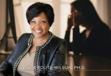 Why Change Fatigue Belongs on the Board Agenda Headshot of Anita Polite-Wilson, Ph.D., - a smiling black woman with short hair wearing an embellished black leather jacket and a beige top - overlaid on a dark backlit image of a woman at her laptop, rubbing her temples