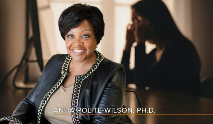 Headshot of Anita Polite-Wilson, Ph.D., - a smiling black woman with short hair wearing an embellished black leather jacket and a beige top - overlaid on a dark backlit image of a woman at her laptop, rubbing her temples